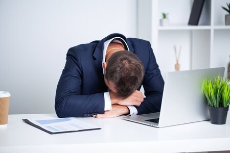 Tired employee working at desk at company office.