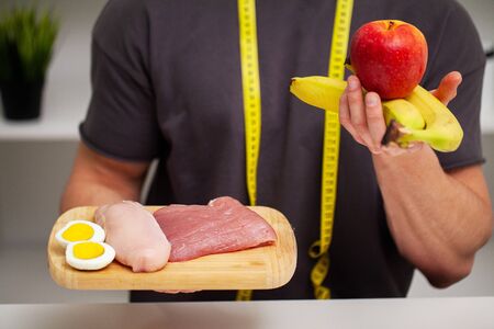 Athletic man holding a board with meat for proper nutrition of the athlete.の写真素材