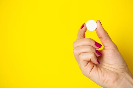 Woman holds white pill in her hand for weight loss