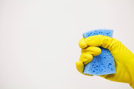 Closeup of hand in yellow mittens holding cleaning suppliesの写真素材