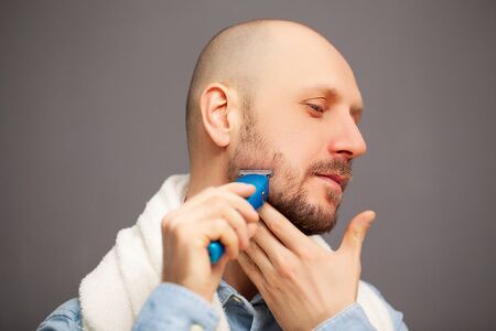 Man trims his beard with an electric typewriterの写真素材