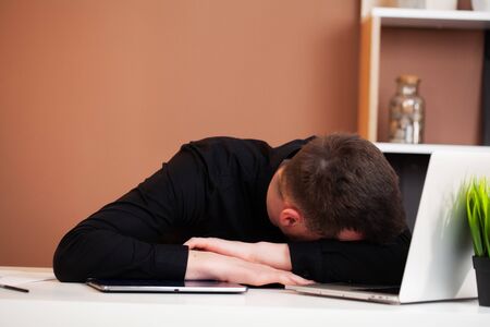 Tired man working at company office at computer.