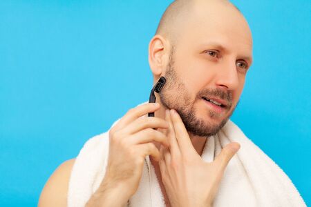 Man in the bathroom shaves his beard with a razor