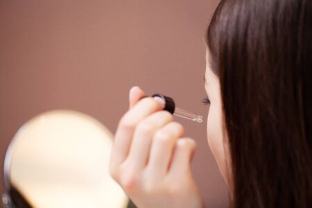 Close up woman uses liquid cream to care for face skinの写真素材