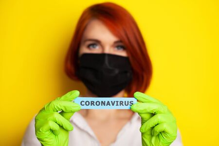 Woman in protective gloves holding inscription coronavirus.の写真素材