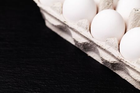 Chicken eggs in a package on a black table