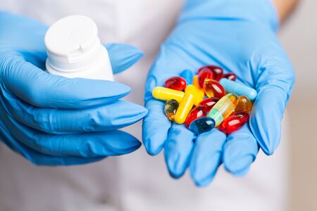Female doctor in gloves holds a pill for treatmentの写真素材