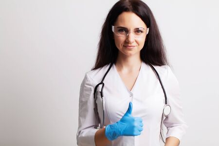 Doctor with protective goggles and stethoscope on her workspaceの写真素材