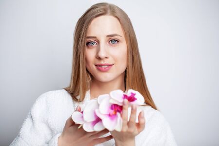Facial care. Young woman with beautiful skin holds an orchidの写真素材