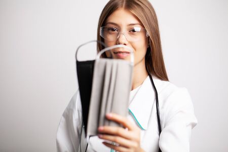 Young doctor woman in glasses holding a protective maskの写真素材