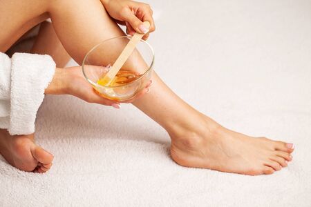 Woman holding a bowl of wax for depilation and skin care.の写真素材