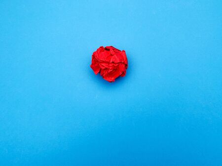 Successful idea concept, red crumpled sheet of paper on blue background.