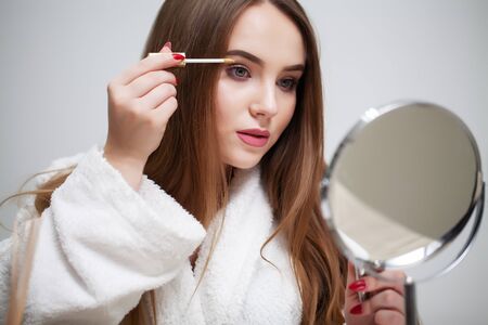 Beauty makeup, young woman with beautiful skin holding eyelash brush near eyesの写真素材