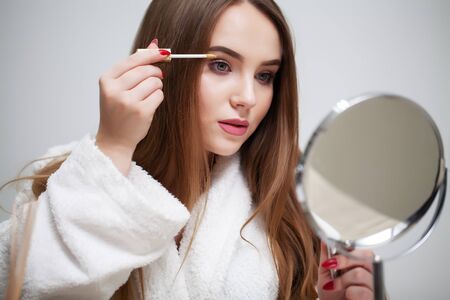 Beauty makeup, young woman with beautiful skin holding eyelash brush near eyes