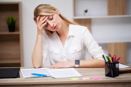 Tired business woman working with documents in the office at the deskの写真素材