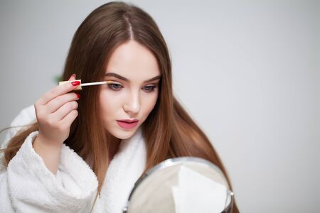 Beauty makeup, young woman with beautiful skin holding eyelash brush near eyesの写真素材