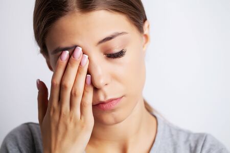 Exhausted young woman suffering severe pain from near the eyes