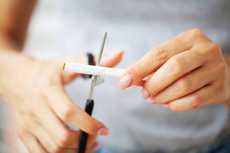 Stop smoking, close up of woman cuts a cigarette with scissors.の写真素材
