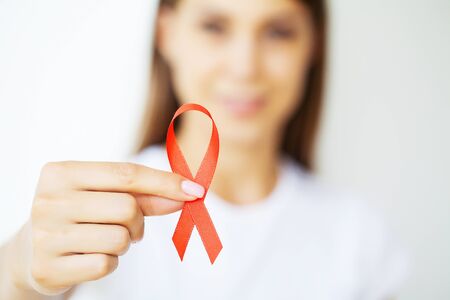 A woman holding a red ribbon emerges from a critical situation after overcoming AIDS