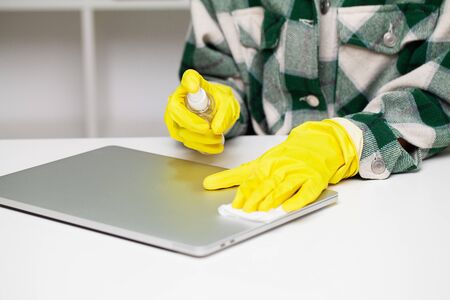 Close up of cleaner in yellow gloves wipes dust in the office.
