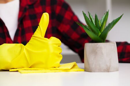 Close up of cleaner in yellow gloves wipes dust in the office.