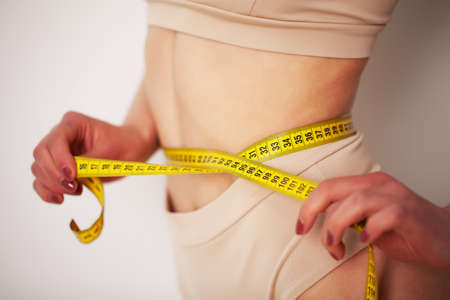 Woman with a sporty figure measures the size of her waist.の写真素材