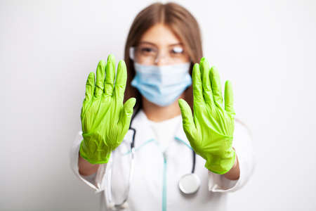 Doctor in gloves and a mask shows a stop with his hands.の写真素材