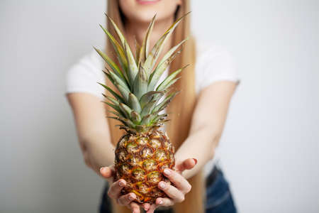 Woman close up holding a ripe pineapple in her hands.の写真素材