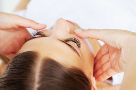 Young woman with beautiful face on facial massage in beauty studioの写真素材