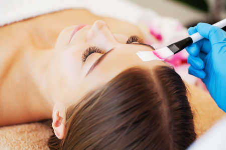 The woman applies a spa mask to moisturize and care for the skin in beauty studio