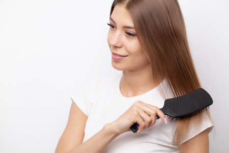 A young girl with beautiful long hair uses a comの写真素材