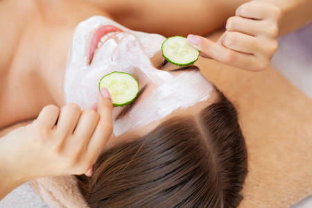Cucumber over the eyes and a white clay mask for facial skin careの写真素材