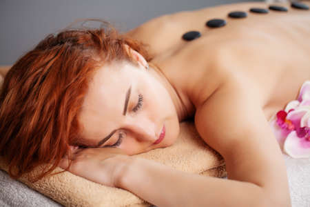 Young woman getting hot stone massage in spa salon.の写真素材
