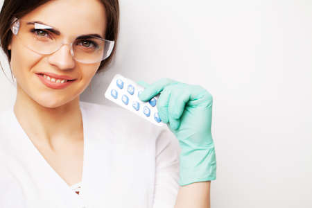 Doctor in a white coat holding a pill for a healthy sex life of men.の写真素材