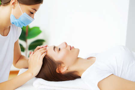 Young beautiful girl having face massage relaxing in spa salon.の写真素材
