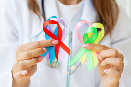 Female doctor holds colored ribbons symbolize awareness of various diseasesの写真素材