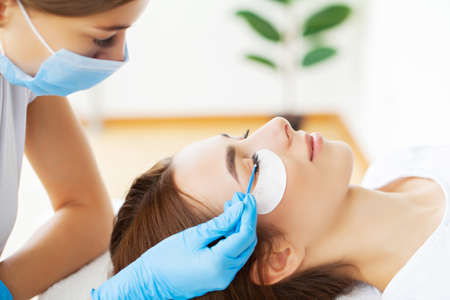 Eyelash extension procedure, professional stylist lengthening female lashes.