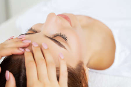 Young pretty woman enjoying face massage procedureの写真素材