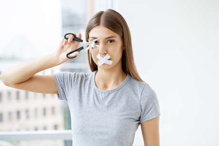 Stop smoking, a woman with a sealed mouth cuts a cigarette with scissors