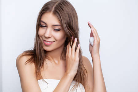 Young woman takes care of her hair using natural oils and conditioners for hair careの写真素材