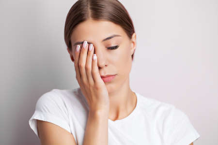 A young woman feels severe pain on her face touching the pain area with her handの写真素材