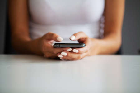 Close up front view young woman holding smartphone, typing message, chatting with friends in social networks.の写真素材