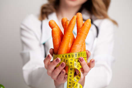 Closeup of woman holding carrot with string tape to measure.の写真素材