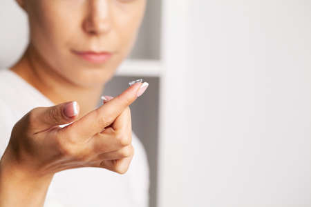 Close up of woman holding contact lens on finger