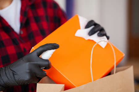 Woman disinfects parcels before unpacking at home