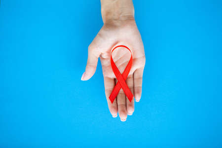 Close Up woman hand holding red ribbon HIV, world AIDS day awareness ribbon.の写真素材