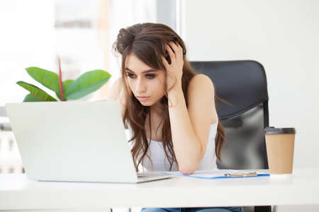 Tired woman in the office working with a laptop