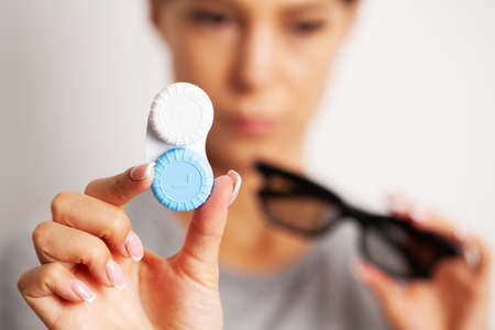 Woman holding plastic container with contact lenses