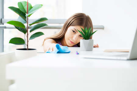 Cleaner tidies up the computer desk in the office.