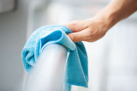 Professional cleaning lady cleans table using a sponge and sprayの写真素材